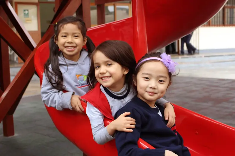 Tres niñas de Early Years de Monterrico Christian School en el tobogán del colegio
