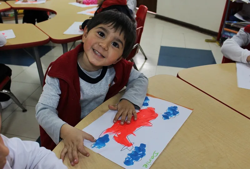 Niño de inicial de 3 años pintando en el aula
